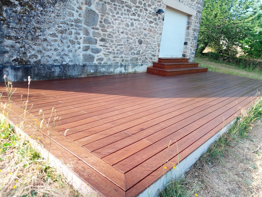 Terrasse en lames de bois exotique le long d'une façade en pierre