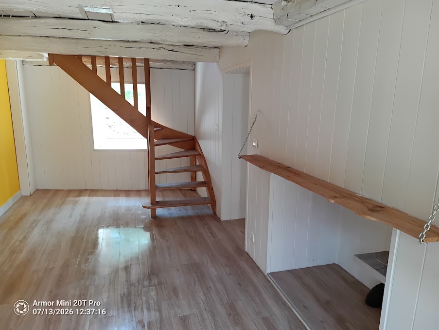 Pièce rénovée avec escalier bois quart tournant et poutres apparentes